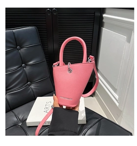 Détail du sac seau rose en cuir grainé avec poignée incurvée et anneaux métalliques