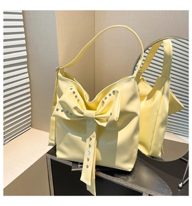 Detailansicht der hellgelben Handtasche mit großer Schleife und silbernen Strasssteinen