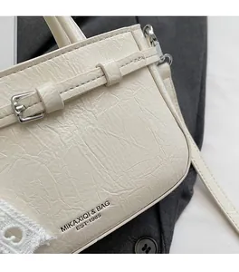 Detail of retro pleated cream PU leather handbag with elegant texture and metal buckle