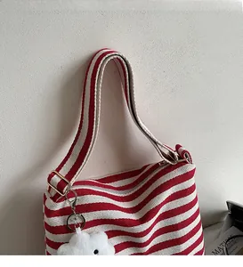 Close-up of a red and white striped canvas tote bag with an adjustable strap and cloud charm