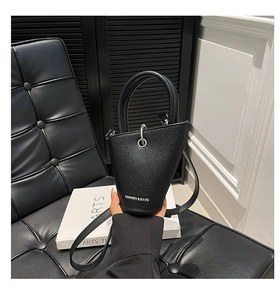 Gros plan détaillé d'un sac seau noir en cuir texturé avec des détails argentés