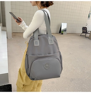 Detailansicht der wasserabweisenden Nylonstruktur und des Logos auf dem grauen Rucksack