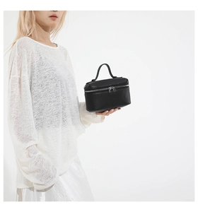 Detail of black lychee texture leather handbag with dual zippers and top handle