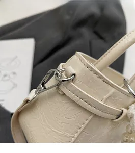 Detail of cream white textured leather handbag with silver hardware and pearl ornament