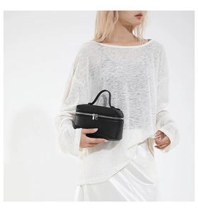 Detail of black pebbled leather mini handbag with silver zipper and top handle