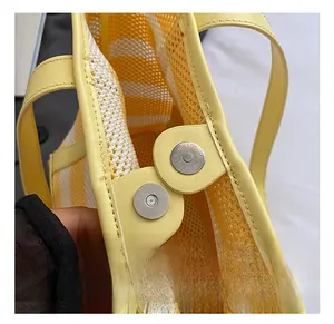 Close-up of magnetic silver metal clasp and yellow leather trim on mesh tote bag