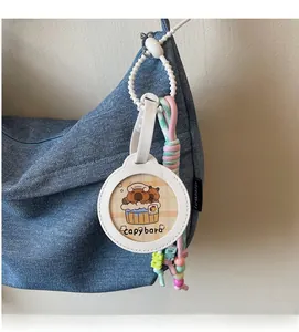 Close-up of a cute capybara leather charm with woven rope on a denim bag shoulder strap