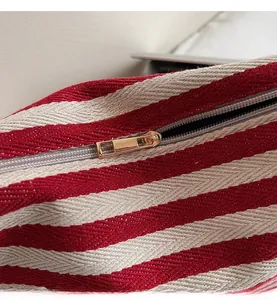 Close-up of a premium gold metal zipper on a red and white striped canvas tote bag