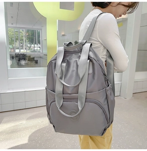Seitenansicht eines grauen wasserdichten Nylon-Rucksacks, getragen von einem Modell im Flur