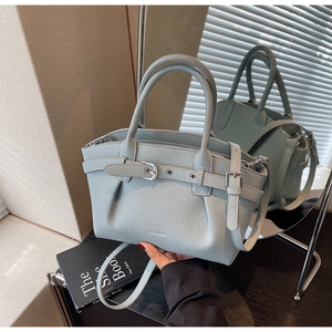 Detail of light blue lychee pattern leather bag with silver buckle and brand logo