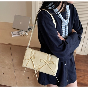 Détail du sac à bandoulière en cuir blanc crème avec décoration de nœud en ruban élégant