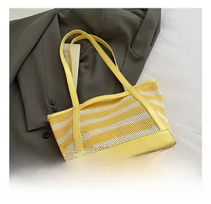 Detail view of yellow striped woven tote bag with premium leather base and handles