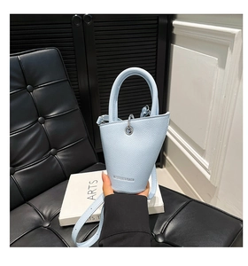 Détail d'un sac seau bleu clair avec texture grainée et poignée supérieure unique