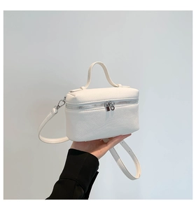 Detail of white lychee leather texture and silver dual zippers on minimalist box bag
