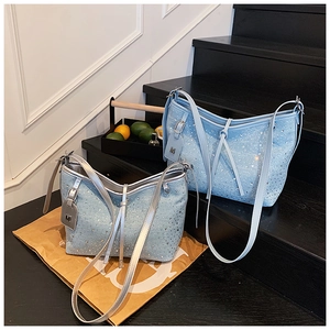 Detailansicht der hellblauen Denim-Beuteltaschen mit glitzernden Strasssteinen und M-Anhänger