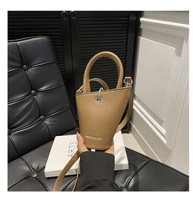 Détail d'un sac seau en cuir grainé kaki avec anneaux argentés et logo imprimé