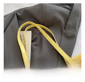 Close-up of bright yellow faux leather handles on a striped woven tote bag detail