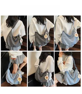 Detailed view of large denim hobo bag with charms, showing grey and blue models on shoulder