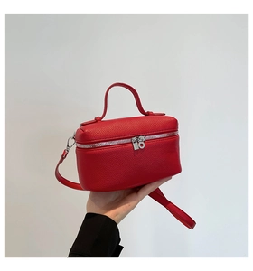 Detail view of red pebbled leather camera bag featuring silver zipper and top handle
