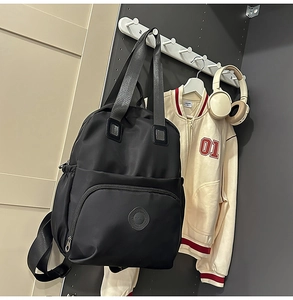 Details des schwarzen wasserfesten Nylon-Rucksacks mit Doppelgriffen und Logo-Prägung