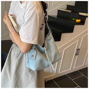 Detail der hellblauen Denim-Schultertasche mit Strasssteinen und Metall-M-Anhänger