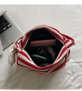Spacious interior of red and white striped canvas tote showing laptop and cosmetics storage