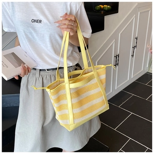 Detail of yellow and white striped mesh tote bag with drawstrings in lifestyle setting