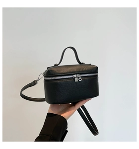 Detail of black lychee grain leather handbag with silver zippers and top handle