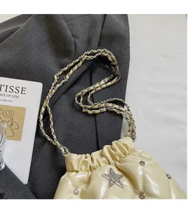 Détail d'un sac seau matelassé beige avec une étoile en cristal et chaîne dorée