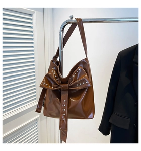 Detail einer dunkelbraunen Hobo-Tasche mit großer Schleife und funkelnden Silbersteinen