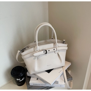 Detail of premium lychee texture leather on cream handbag with brand logo and buckle