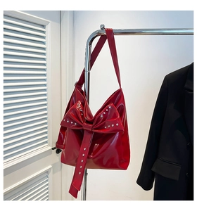 Detail einer roten Lacklederhandtasche mit großer Schleife und silbernen Strassakzenten