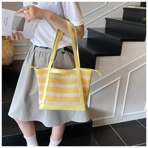 Detail of yellow and white striped mesh tote bag featuring leather handles and drawstring