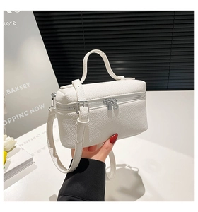 Detailed close-up showing the litchi grain texture and silver hardware of the white handbag