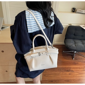 Detail of cream pleated leather handbag with metallic clasp and brand lettering