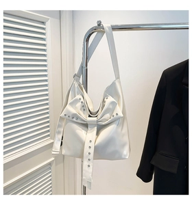Detail der weißen Lackledertasche mit großer Schleifendekoration und silbernen Nieten