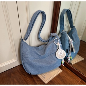 Detail of light blue denim hobo bag with capybara charm and UTAVIAN brand tag