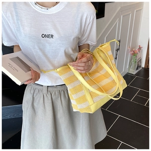 Macro view of mesh tote bag featuring yellow and white stripes with drawstring detail