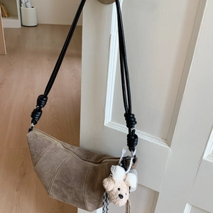 Détail du sac croissant en daim marron avec bandoulière à nœuds et pendentif ours