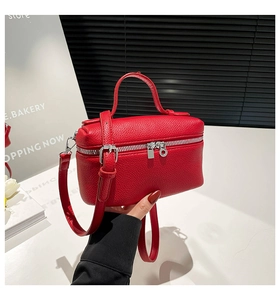 Detail of red litchi texture leather small box bag with silver zippers and top handle