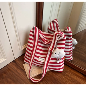 Detail of red striped canvas tote bag with plush cloud charm and adjustable strap