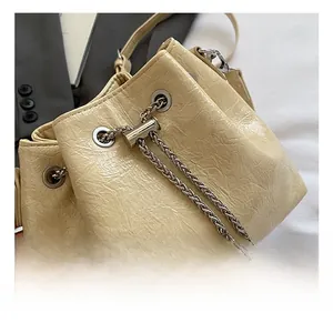 Details der silbernen Hardware und der Faltenlederstruktur auf der cremefarbenen Beuteltasche