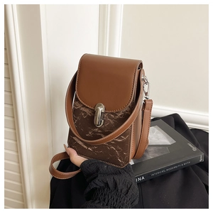 Détail d'un sac bandoulière en cuir marron avec motif marbré et fermoir rotatif argenté