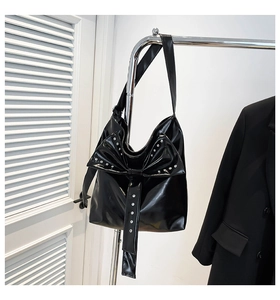 Detail der schwarzen Lackleder-Tasche mit großer Nieten-Schleife und Nietenbesatz