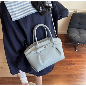 Close-up of light blue pebbled leather handbag with ZHONMA branding and buckle detail