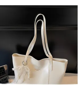 Detail view of cream white tote bag with elegant lace pearl charm and brand logo