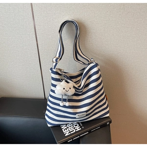Blue and white striped canvas tote bag detail with cute cloud plush charm and brand label