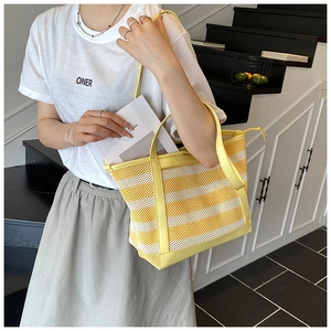 Striped mesh tote bag with leather trim carried by model in a minimalist setting
