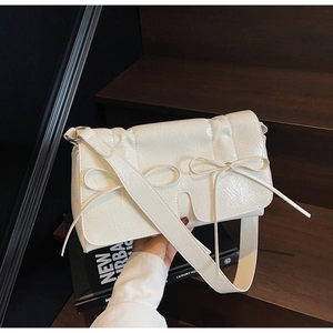 Détail du sac à bandoulière en cuir plissé blanc crème avec nœuds papillon élégants
