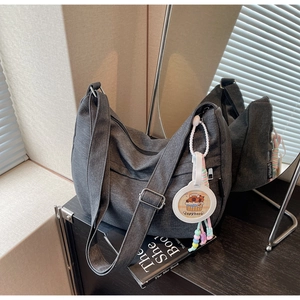 Detail of grey denim dumpling bag with adjustable strap and capybara charm